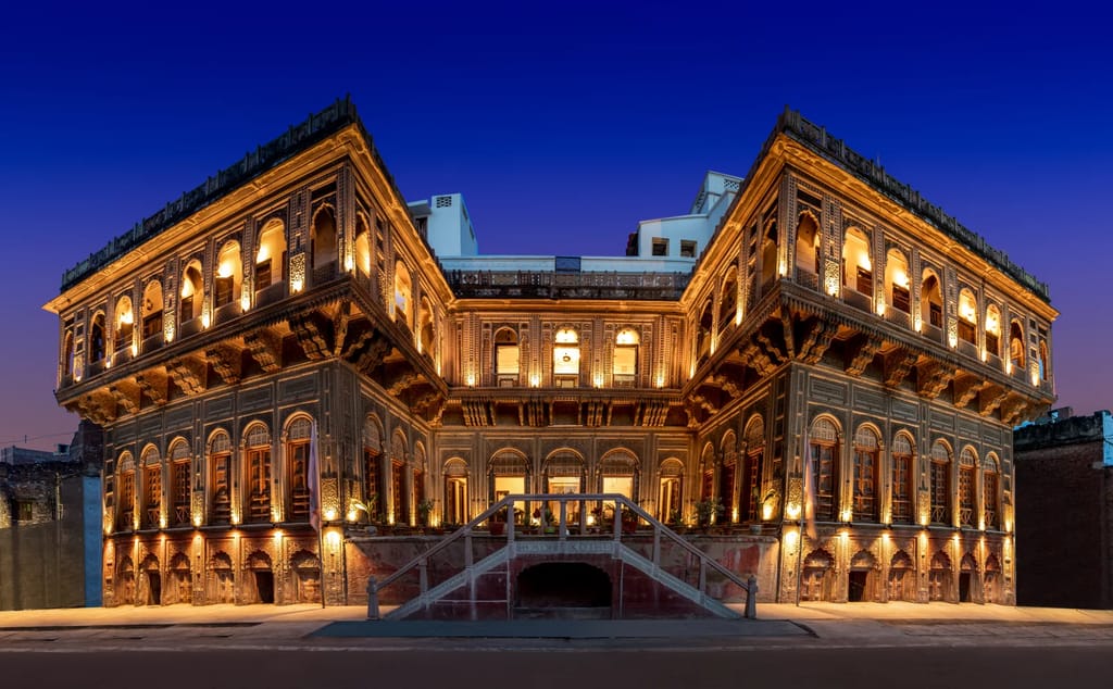 WelcomHeritage Badi Kothi lit up at night, carved sandstone facade