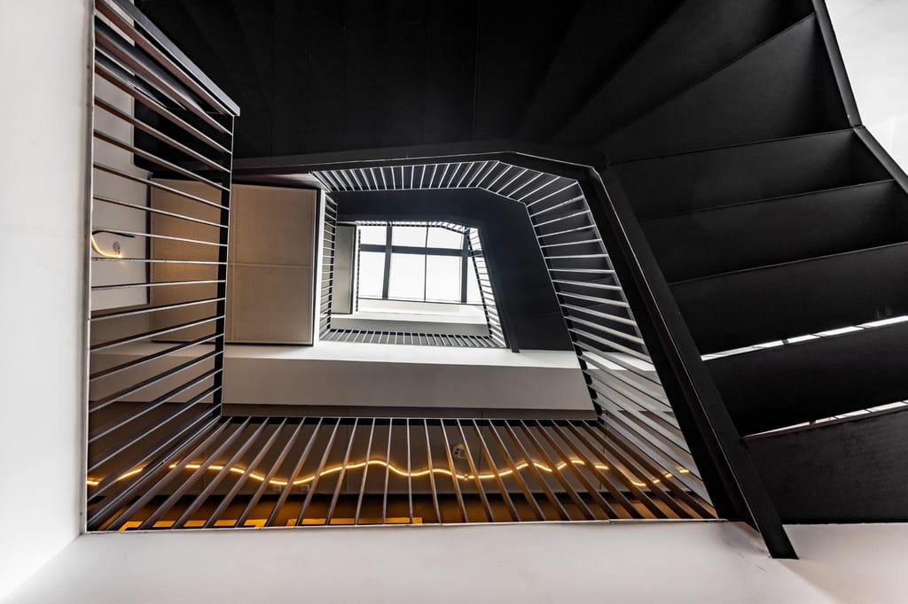 Black steel stairwell atrium with lit signage and arched window