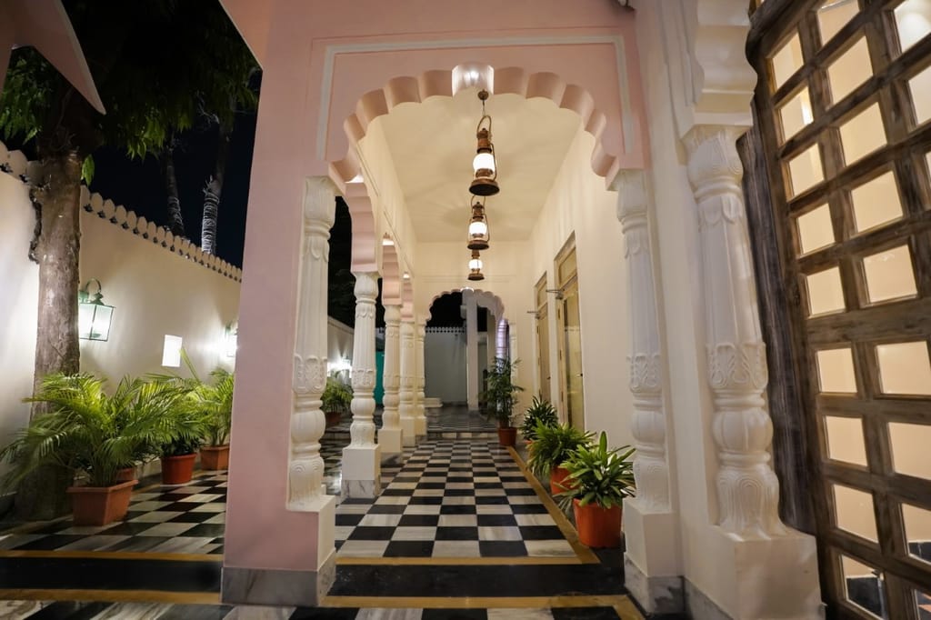 Pink scalloped arches and lanterns along the entrance arcade at Dev Mahal, Jaipur