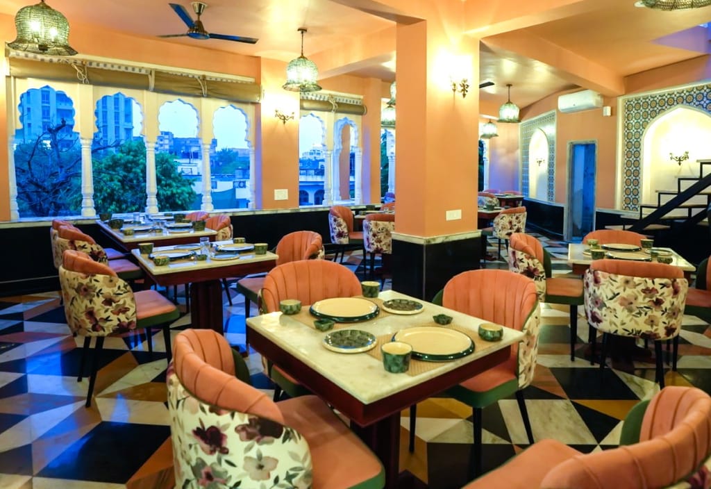 The rooftop restaurant at Dev Mahal at dusk, arches open to the Jaipur skyline