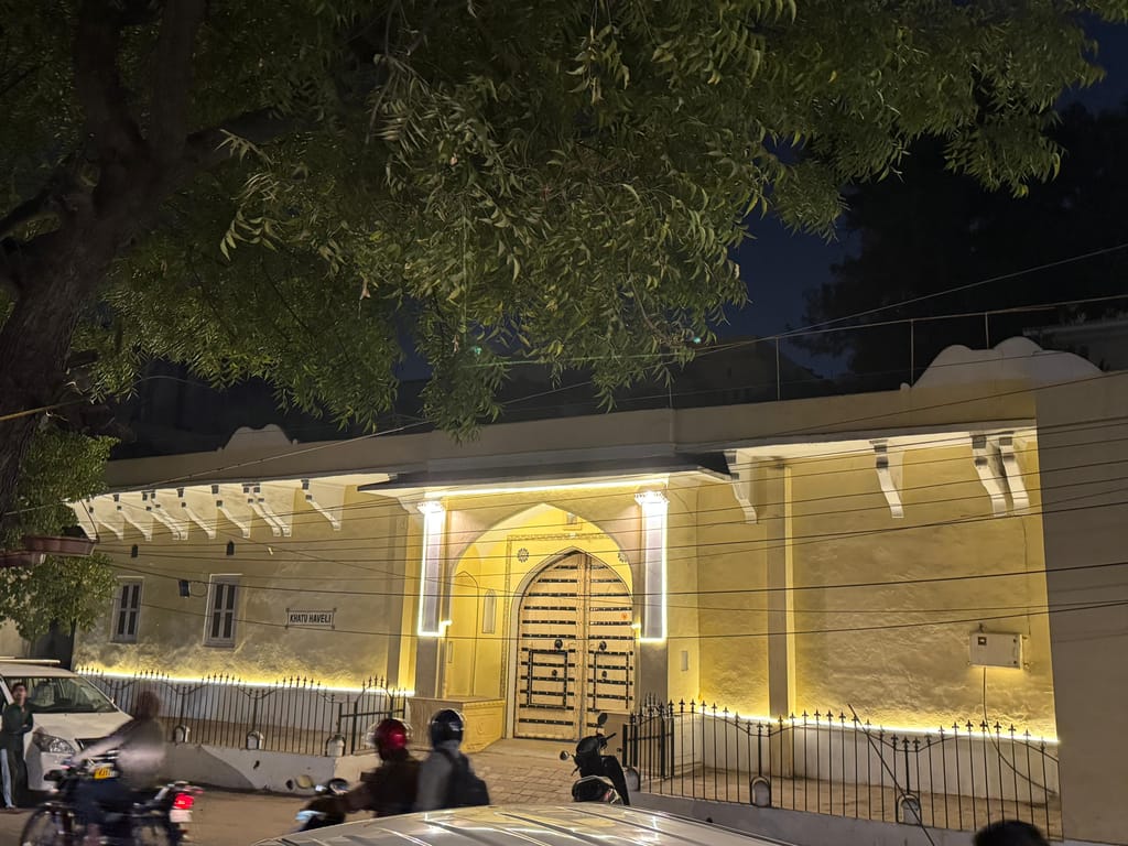 Haveli entrance facade lit at night from the lane