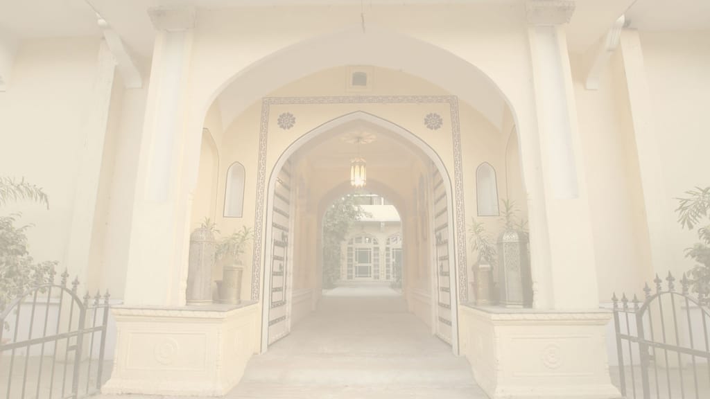 Arched gateway view into the haveli (site hero image, pale overlay baked in)