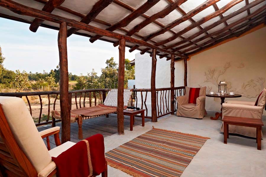 Villa private deck with day-bed, rustic timber pergola and striped rugs overlooking the landscape at Samode Safari Lodge, Bandhavgarh