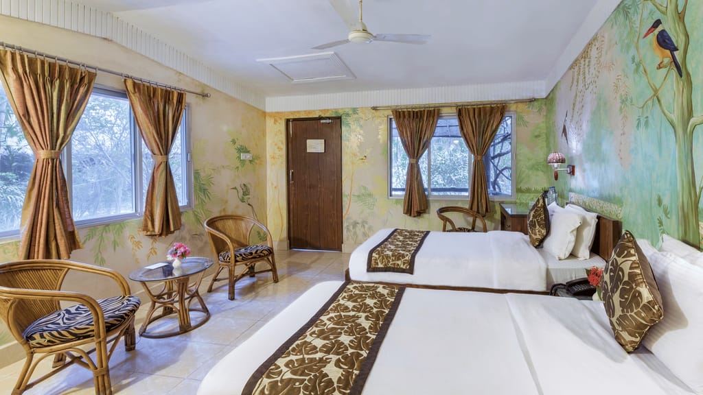Executive Cottage — twin beds and cane seating surrounded by hand-painted jungle murals at Sundarban Tiger Camp, Sundarbans