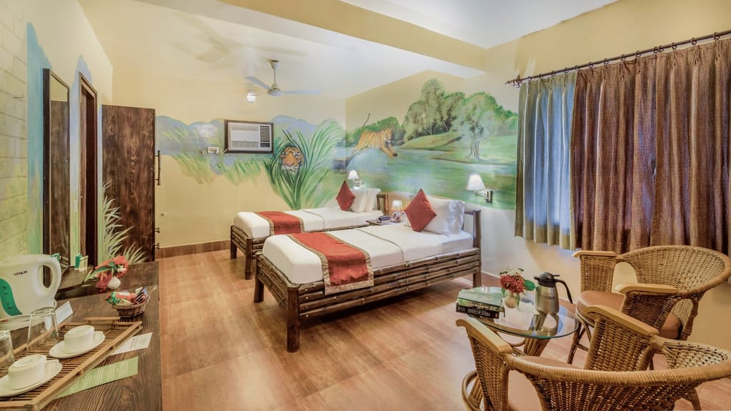 Executive Cottage — bamboo twin beds beneath a tiger mural with cane seating area at Sundarban Tiger Camp, Sundarbans