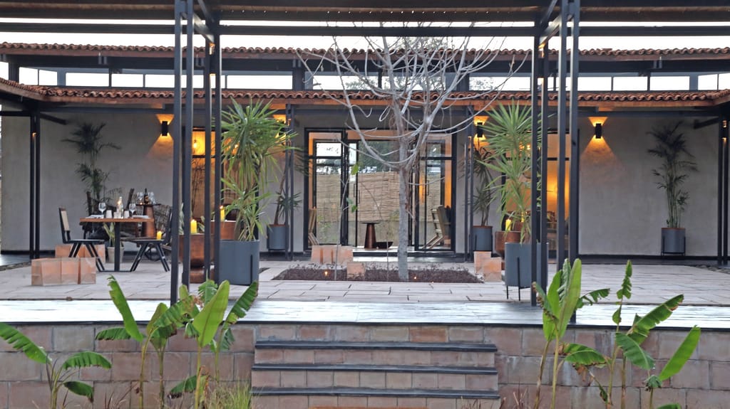 Candle-lit courtyard terrace with tiled roofs and a dining table laid at Bori Safari Lodge, Satpura