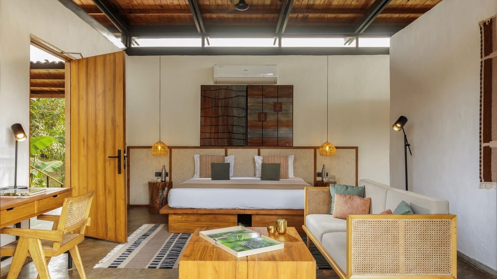 Luxury Room — bedroom with king bed, cane sofa, teak furniture and clerestory windows at Bori Safari Lodge, Satpura