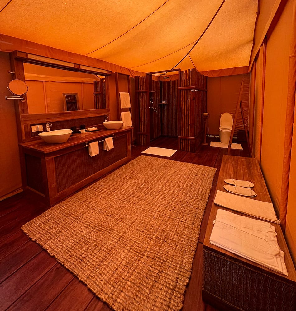 Tented Suite — bathroom with twin basin vanity, jute rug and bamboo-screened shower at Bagh Villas, Kanha