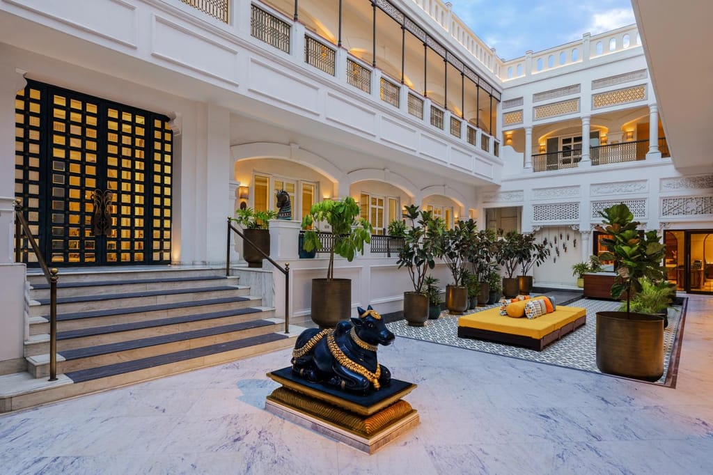 White open-air courtyard with marble steps, Nandi statue and yellow daybed at Pilibhit House, Haridwar