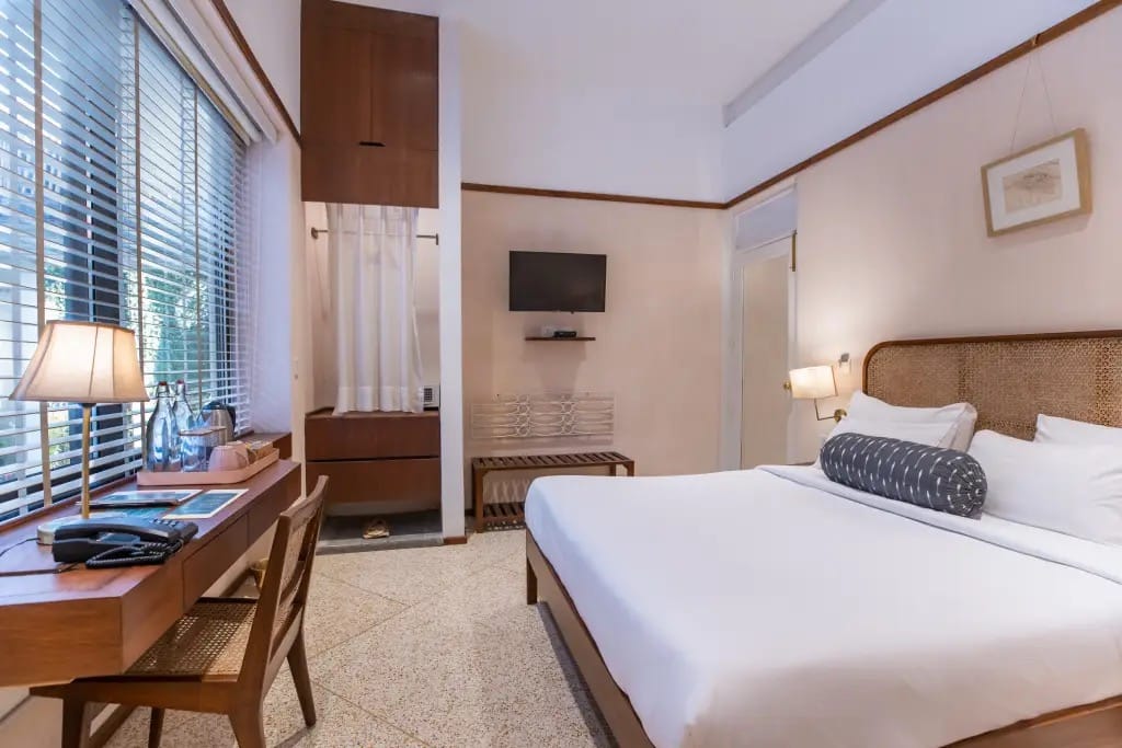 Kratu bedroom with cane headboard, writing desk by the window and terrazzo floor at Amrit Bhawan, Haridwar