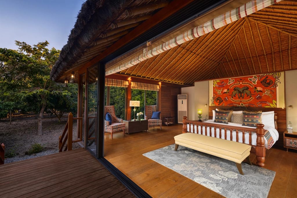 SeleQtions Villa with King Bed under a bamboo-lined roof with deck overlooking the mango orchard at dusk at Jaagir Manor, Dudhwa