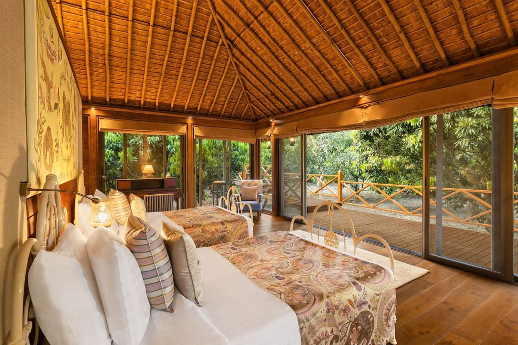 SeleQtions Villa with Twin Bed under a thatched ceiling with glass walls opening to the orchard deck at Jaagir Manor, Dudhwa