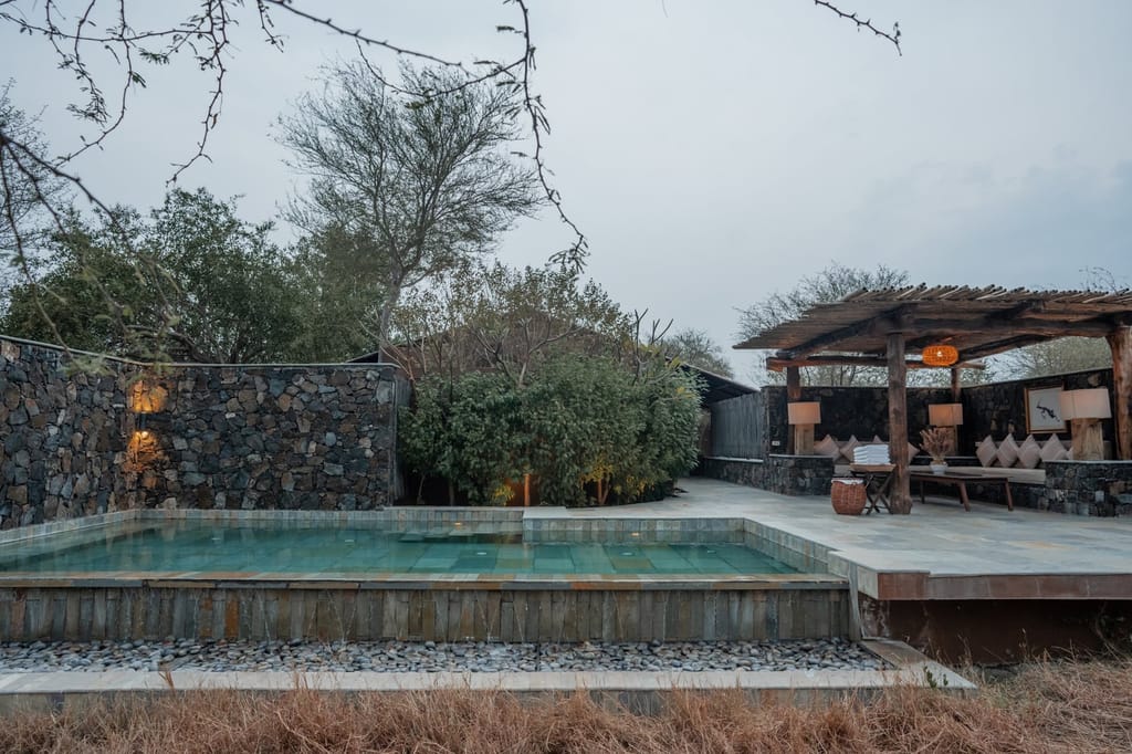 The Pool Villa private pool with stone walls and shaded pergola seating area at The Blackbuck Lodge, Velavadar