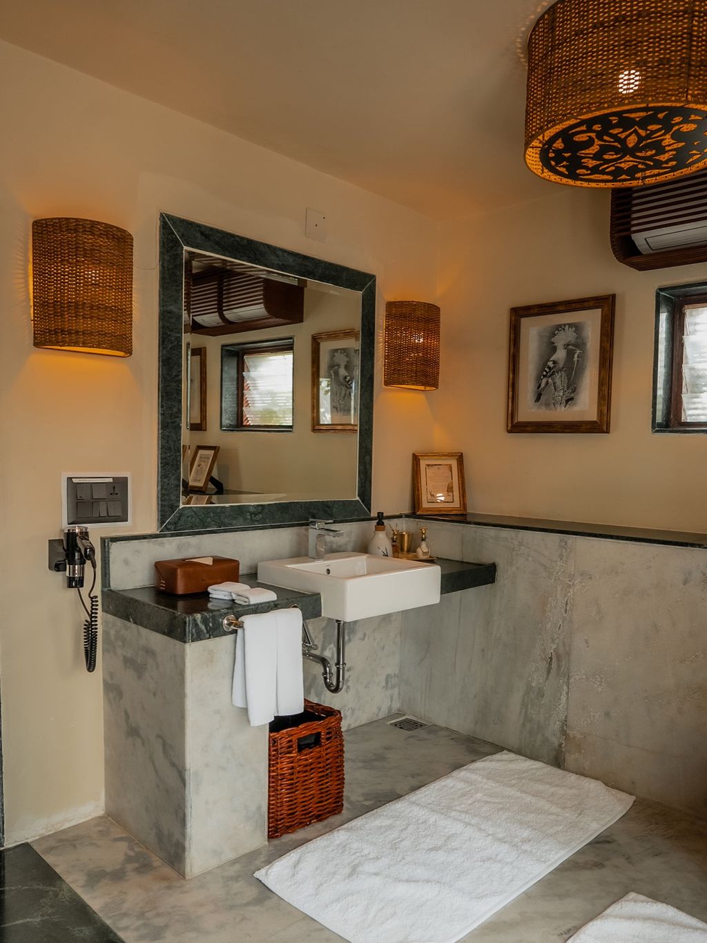 The Villa bathroom with marble vanity, green stone-framed mirror and wicker light shades at The Blackbuck Lodge, Velavadar