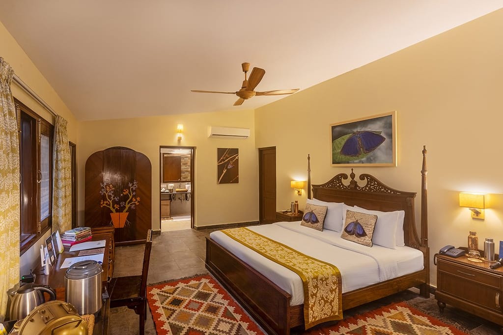 The Wildernest — bedroom with four-poster bed, butterfly artwork and hand-painted wardrobe at Singinawa Jungle Lodge, Kanha