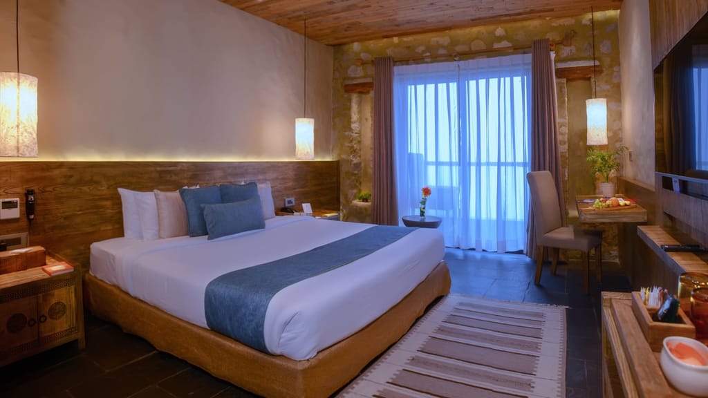 Suites king bed with blue cushions, hanging paper lamps and sheer curtains at Sarangkot Mountain Lodge, Pokhara