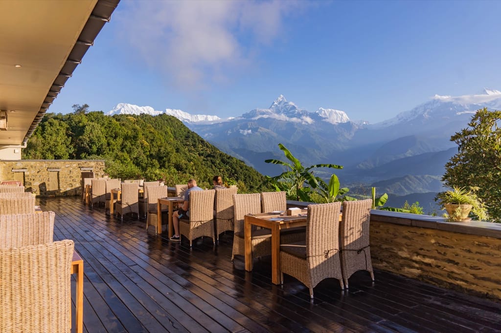 Terrace dining deck with wicker chairs looking out to snow-capped Himalayan peaks at Sarangkot Mountain Lodge, Pokhara