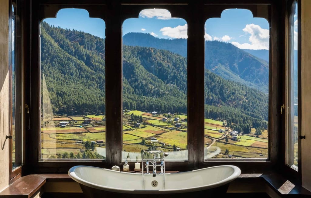 Bhutanese Farmhouse Suite freestanding bathtub set before arched windows overlooking the Phobjikha valley at Gangtey Lodge, Gangtey