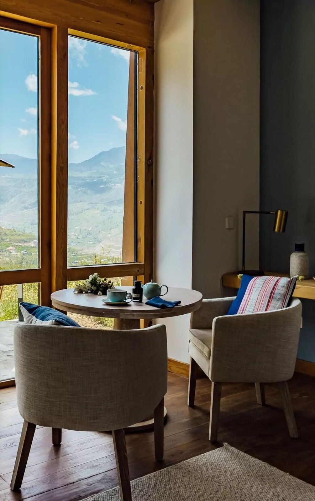 Terrace Room tea table and armchairs beside a picture window with valley views at Bhutan Spirit Sanctuary, Paro