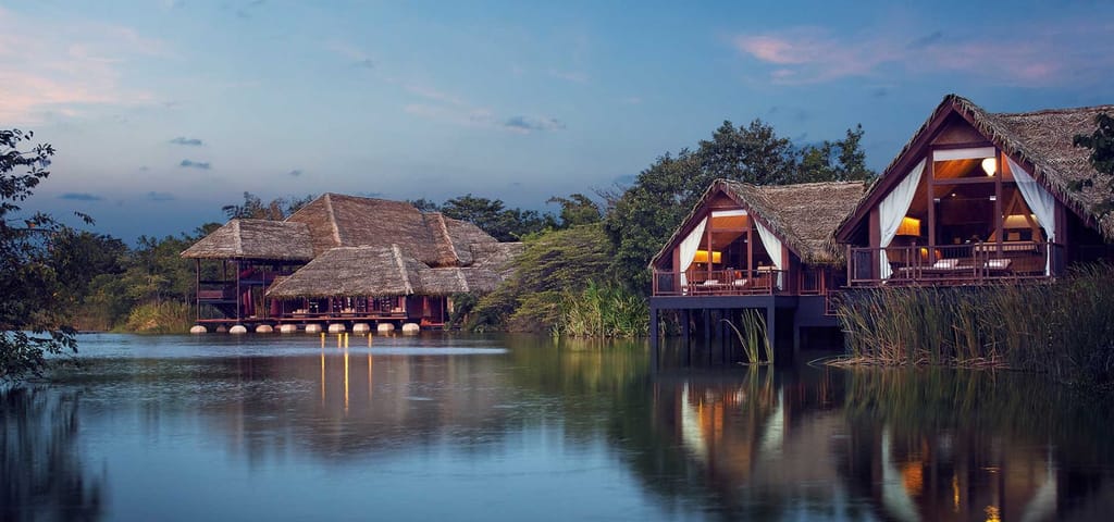 Thatched Water Dwellings on stilts reflected in the lake at dusk at Jetwing Vil Uyana, Sigiriya
