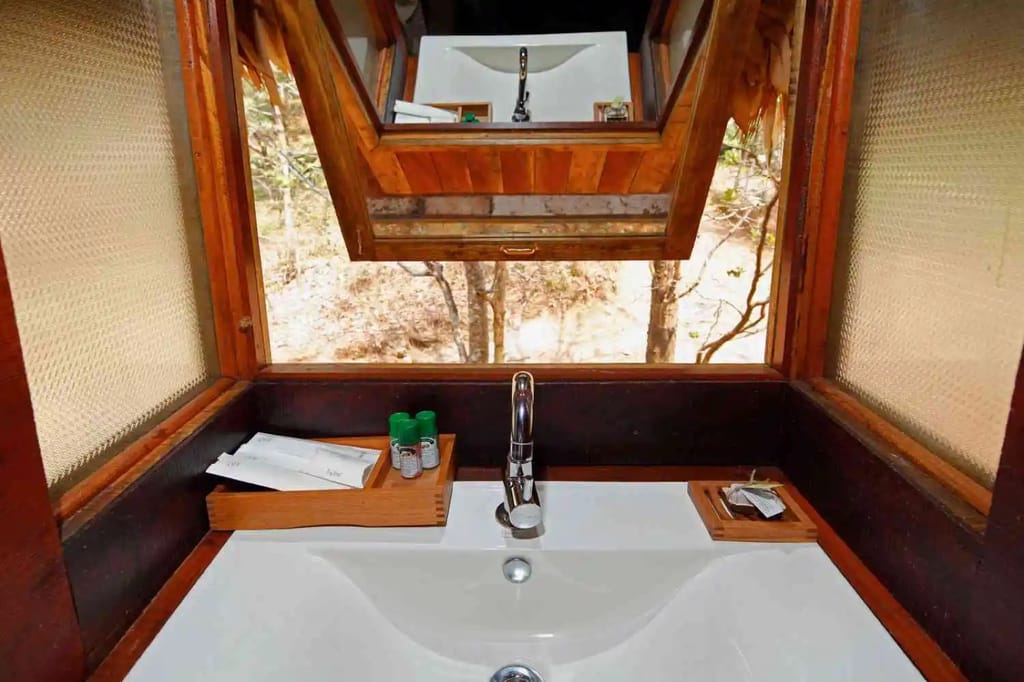 Tree House bathroom washbasin with mirror and an open window onto the surrounding trees, Rainforest Athirapally, Athirappilly