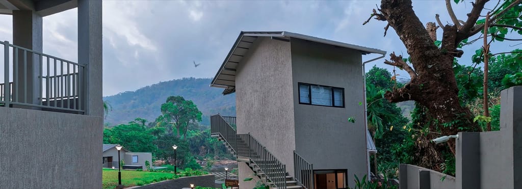 Luxury Cottage exterior with external staircase and forested hills behind, Niraamaya Retreats Samroha, Athirappilly
