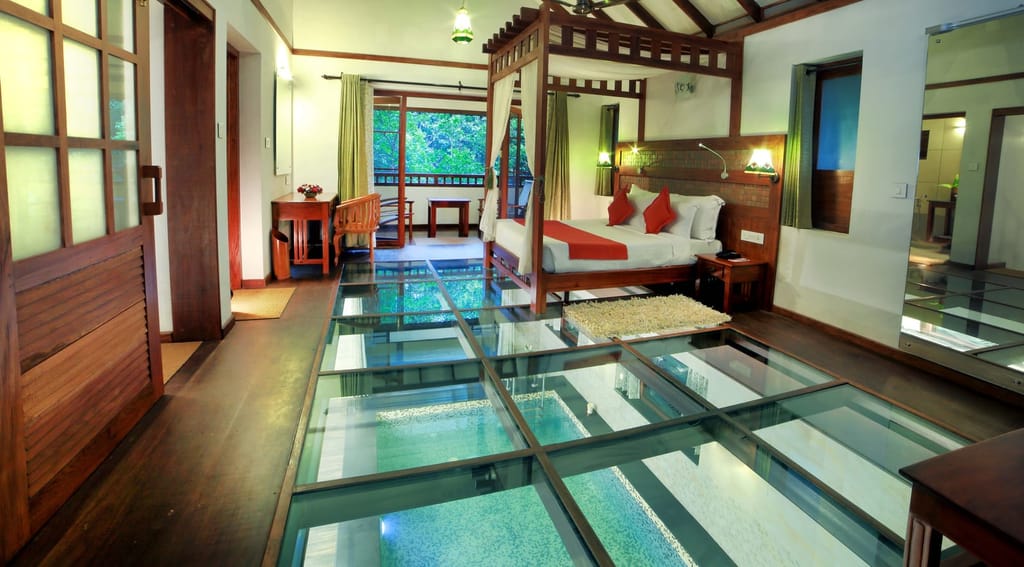 Celestial Honeymoon Pool Villa bedroom with four-poster bed and glass floor over the private pool, Vythiri Resort, Vythiri