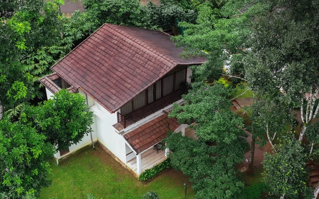 Planters Villa tiled-roof cottage with balcony seen from above among trees, Carmelia Haven, Thekkady