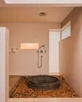 The bathroom of a Heritage Wing room at Kara, a copper tub on pebbles under the rain shower