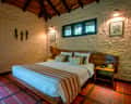 Inside a bungalow at Kanha Earth Lodge, the bed under a timber roof
