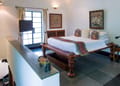 Upstairs bedroom of The Malabar Suite at The Malabar House with a carved wooden bed and black stone floor