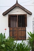 Timber-shuttered window under a gabled eave on a garden cottage at Old Harbour Hotel