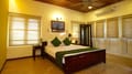 Tea Bungalow, Fort Kochi: Heritage Premium Room with wood-panelled ceiling, bamboo blinds and green cushions on a wooden bed
