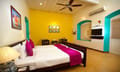 Tea Bungalow, Fort Kochi: Heritage Deluxe Room with yellow walls, turquoise-framed alcove, wall-mounted TV and bed with pink throw