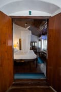 Superior Room at The Old Courtyard Hotel seen through its wooden door: twin beds under a mosquito net and a wall of windows