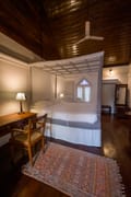 Superior Room with a large double bed on the second floor of The Old Courtyard Hotel, writing desk and rug on dark timber floor