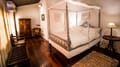 Superior Room at The Old Courtyard Hotel with a four-poster bed, antique wardrobe and side table