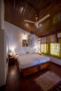 Standard Room at The Old Courtyard Hotel, twin beds beneath a timber ceiling at the top of the spiral staircase