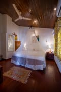 Standard Room with twin beds under a mosquito net at The Old Courtyard Hotel, timber ceiling and patterned rug