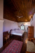 Deluxe Twin room at The Old Courtyard Hotel with antique wardrobe, chair and red carpet on polished floorboards