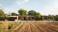 Low villa building across a ploughed farm field