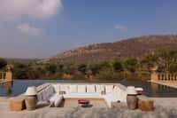 Infinity pool with white daybeds facing hills