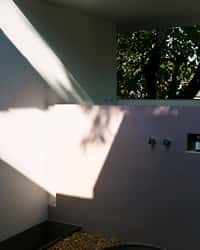 Open-to-air bathroom wall with tree shadows