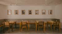 Cafe tables and bench under a row of framed prints