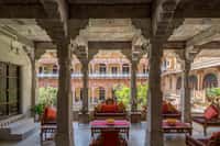 Pillared verandah with red cushioned benches looking out across the courtyard