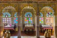 Dining hall with hand painted arches and stained glass windows, tables laid for a meal