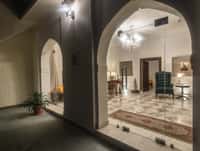 Arched corridor at night looking through to a lounge lit by a chandelier