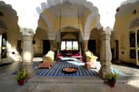 Open pillared hall of scalloped arches with a hanging swing seat and floor cushions