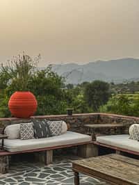 Stone lounge terrace with day beds facing the Aravallis