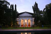 Manor facade lit at dusk seen across the pool